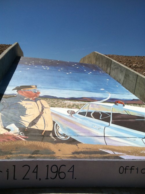 A mural depicting a police officer and a vintage car under a starry sky, with the date "11 24, 1964" at the bottom.