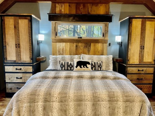 Cozy bedroom with a wooden theme, featuring a large bed, bear-themed decor, and rustic cabinets on either side.