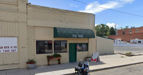 A small building with a green awning labeled "Tree Sang," featuring a motorcycle parked outside.