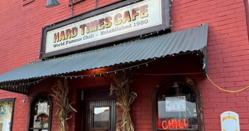 Exterior of Hard Times Cafe, featuring a red brick facade, a sign for "World Famous Chili," and autumn decorations.