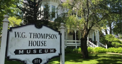 A historic house museum with a sign reading "W.G. Thompson House Museum" in a lush green setting.