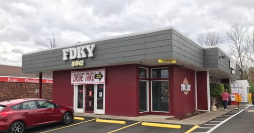 A red and gray building with a sign for "FDKY BBQ" and a drive-thru entrance, surrounded by a parking lot.