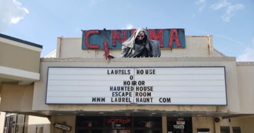 A cinema marquee advertising "Laurel's House of Horror" and an escape room, with a spooky figure above.