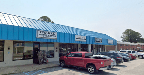A row of storefronts with blue roofs, featuring signs for "Frank's Monster & Miniatures" and "Southern Comfort."