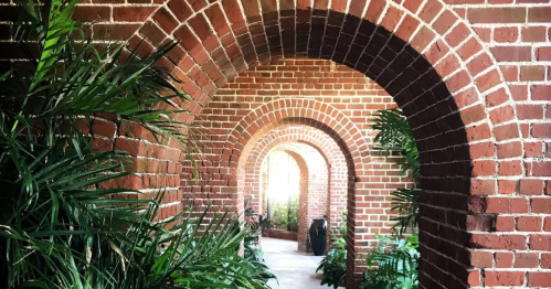 A series of brick arches lined with greenery, creating a serene corridor effect.