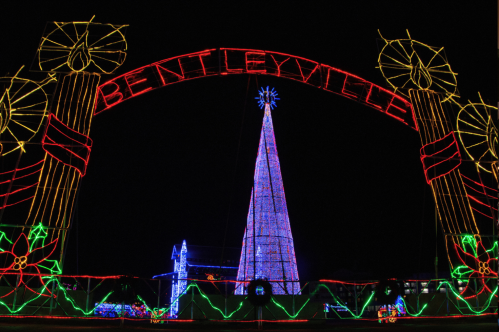 Colorful holiday lights form an arch reading "Bentleyville" over a tall, illuminated Christmas tree.