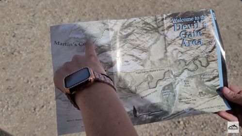 A person points at a map of the Devil's Gate Area, highlighting Martin's Cove, with a watch on their wrist.