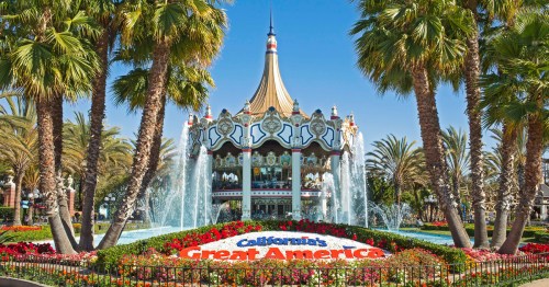 A colorful carousel surrounded by palm trees and flowers at California's Great America amusement park.