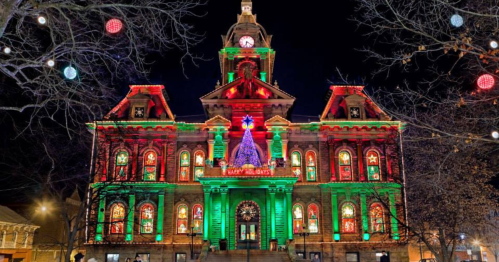 Historic building illuminated with colorful holiday lights, featuring a large Christmas tree and festive decorations.
