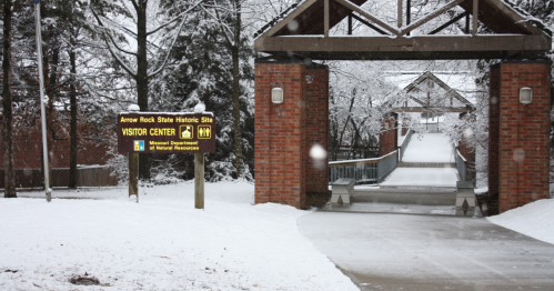 Snow-covered path leading to a visitor center at Amour Rock State Historic Site, with a sign indicating the location.