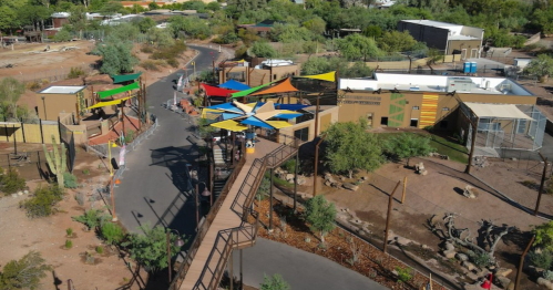 Aerial view of a colorful outdoor area with pathways, buildings, and greenery in a desert landscape.