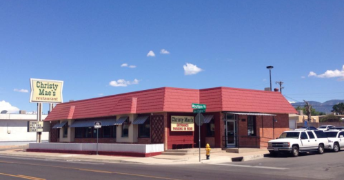 A red-roofed restaurant building with a sign reading "Christy Mae's" on a sunny day, located at a street corner.