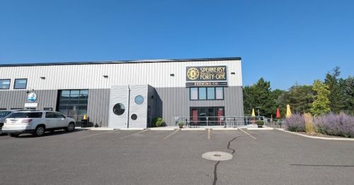 Exterior of Speakeasy Forty-One Brewing Co. with a clear blue sky, parking lot, and outdoor seating area.