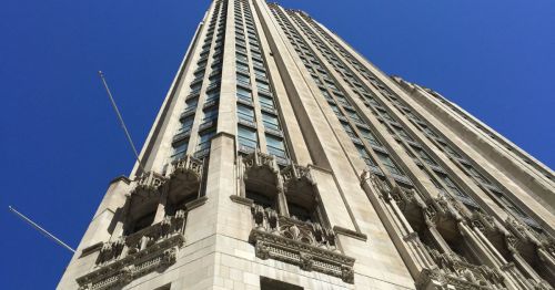 A tall, ornate skyscraper with intricate architectural details against a clear blue sky.