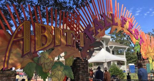 Colorful entrance sign for the Abita Fall Fest, with vibrant decorations and a clear blue sky in the background.