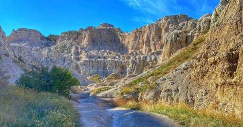 A scenic view of rugged rock formations and grassy terrain under a clear blue sky.