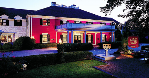 A charming pink and white house at dusk, featuring a welcoming entrance and landscaped gardens.