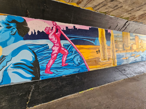 Colorful mural depicting a figure in pink wading through water, with cityscapes and a blue background.