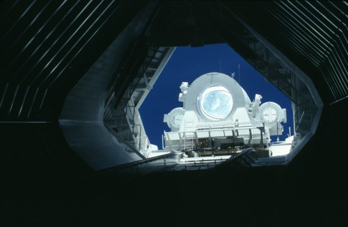 View from inside a spacecraft, looking out at a bright blue sky and a large, illuminated moon through a circular window.
