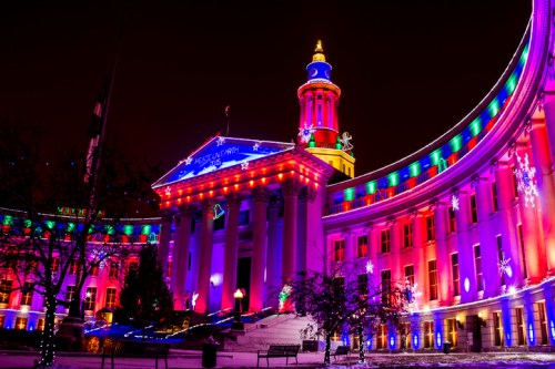 A brightly lit historic building at night, adorned with colorful holiday lights and decorations.