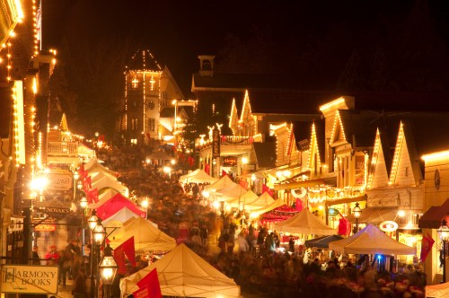 A bustling night market illuminated by string lights, with tents and crowds filling a charming street.