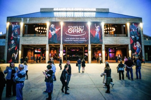 Crowd outside the Grand Ole Opry House, featuring banners and a lively evening atmosphere.