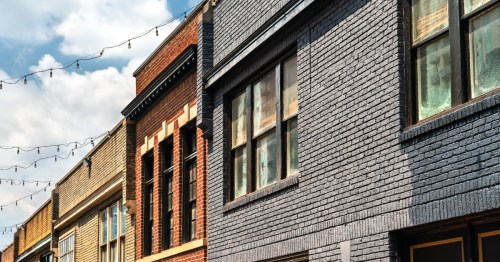 Close-up of historic downtown brick buildings with string lights overhead.
