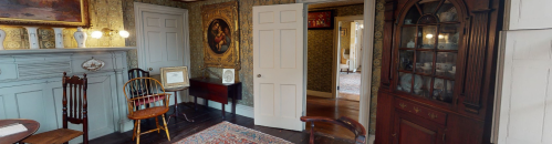 A cozy room with vintage furniture, a patterned rug, and a doorway leading to another space.