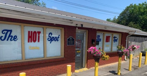 Exterior of "The Hot Spot" restaurant with colorful signage and flower planters on a sunny day.