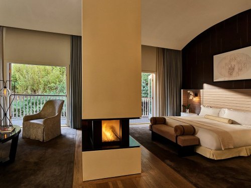 Modern hotel room featuring a cozy fireplace, large windows, and stylish furnishings.