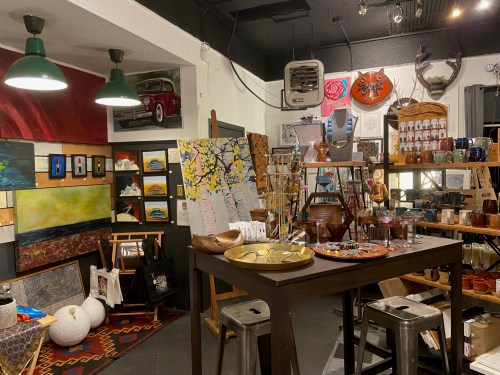 A cozy art shop filled with colorful paintings, crafts, and decorative items, featuring warm lighting and unique displays.
