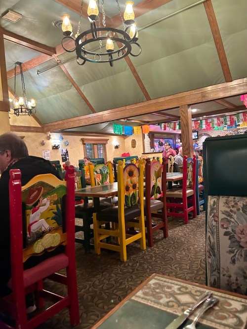 Colorful chairs and festive decor in a cozy restaurant interior, with patrons enjoying their meals.