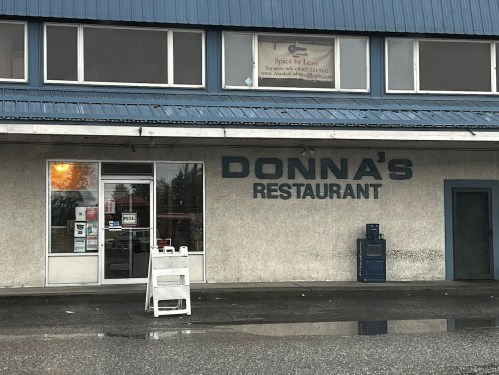 Exterior of Donna's Restaurant, featuring a blue roof, large windows, and a sign indicating space for lease.