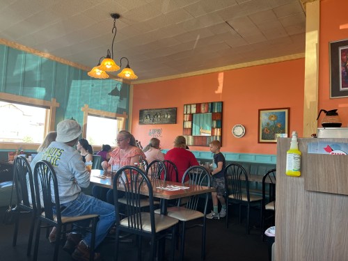 A cozy restaurant interior with colorful walls, tables, and patrons enjoying their meals.