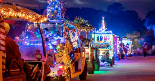 A line of decorated golf carts with colorful lights, set against a twilight sky.