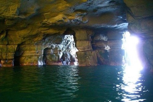 A serene cave interior with water reflecting light from openings, creating a tranquil atmosphere.