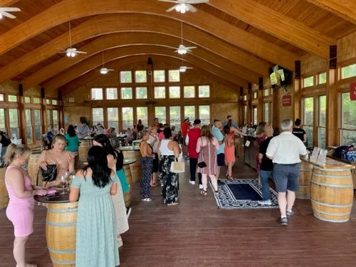 A spacious venue with wooden beams, filled with people mingling and enjoying a gathering or event.