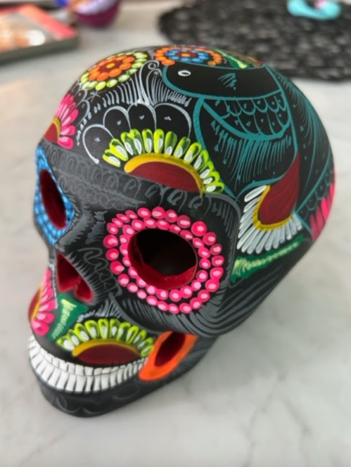 Colorful decorative skull with intricate floral patterns and vibrant details, resting on a marble surface.