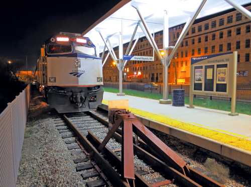 Amtrak train at night at Grand Rapids station, with illuminated platform and buildings in the background.