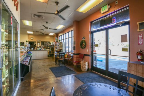 Interior of a cozy café with tables, a display case, and a welcoming entrance. Bright and inviting atmosphere.