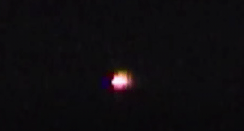 A small, colorful light appears against a dark background, possibly indicating an object in the night sky.