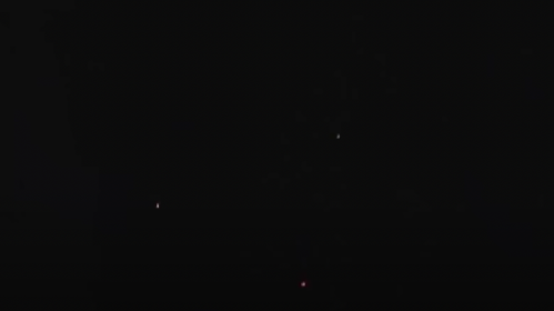 A dark sky with scattered bright points of light, resembling stars or distant celestial objects.