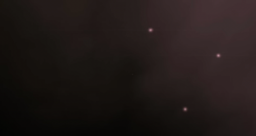 A dark, blurred background with several faint, glowing white dots scattered across the scene.