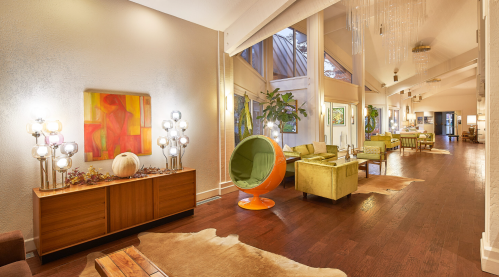 A stylish, modern lounge with colorful furniture, artwork, and large windows, featuring a cozy, inviting atmosphere.