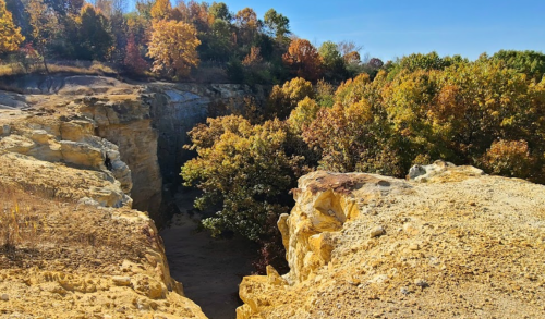 A scenic view of a rocky canyon surrounded by vibrant autumn foliage under a clear blue sky.