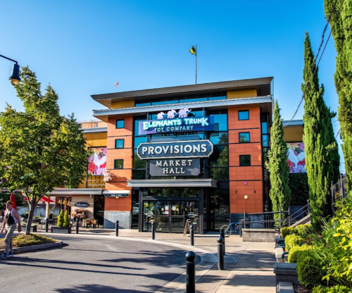 Colorful building exterior featuring "Elephant's Trunk Toy Company" and "Provisions Market Hall" signage under a clear blue sky.