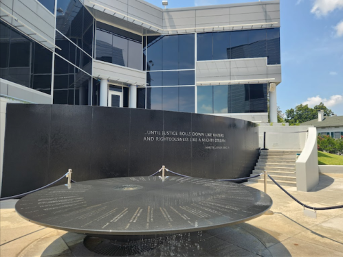 A modern building with a circular water feature inscribed with a quote about justice and righteousness.