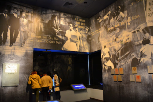 Visitors explore a museum exhibit featuring historical black-and-white photographs on the walls.