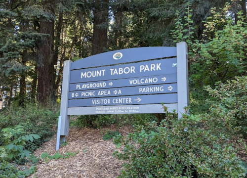 Sign for Mount Tabor Park with directions to playground, volcano, picnic area, parking, and visitor center.