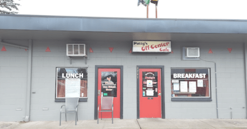 Exterior of Patty's Off-Center Cafe, featuring a gray building with red doors and signs for lunch and breakfast.